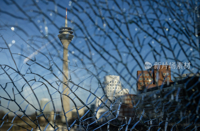 莱茵塔(Rheinturm)和Düsseldorf MedienHafen(媒体港)的天际线，包括盖里建筑，Neuer Zollhof，透过破碎的玻璃观看